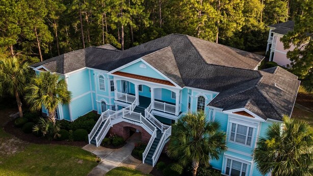 A large, two-story house with a wrap-around porch, surrounded by lush greenery and tall trees. - Oh Whale Pawleys Island SC (Pawleys Island)