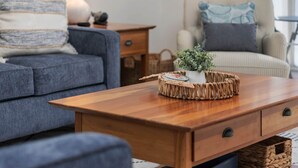 A cozy living room with a grey sofa, a wooden coffee table with a woven basket, and a striped armchair with a blue pillow. - Oh Whale Pawleys Island SC (Pawleys Island)