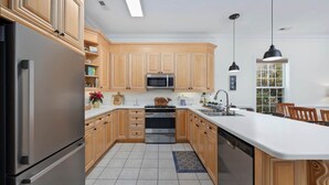A modern kitchen with wooden cabinets, stainless steel appliances, and a large island with a sink. - Oh Whale Pawleys Island SC (Pawleys Island)