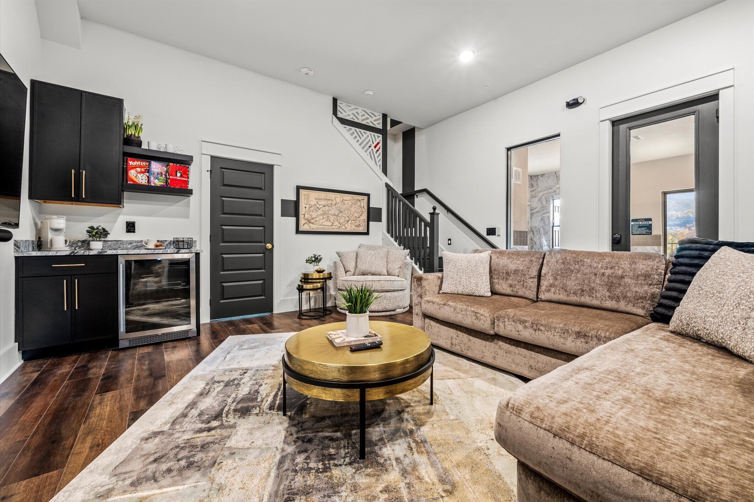 A modern living room with a sofa, coffee table, and kitchen area with cabinets and a refrigerator.