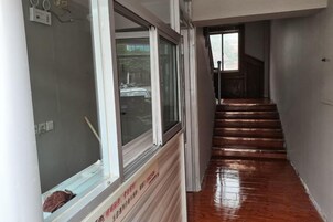 Un pasillo con una escalera de madera que sube a un piso superior.