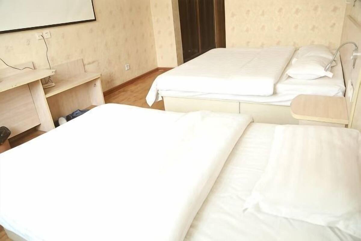 Une chambre d’hôtel avec deux lits, un bureau en bois et un miroir.