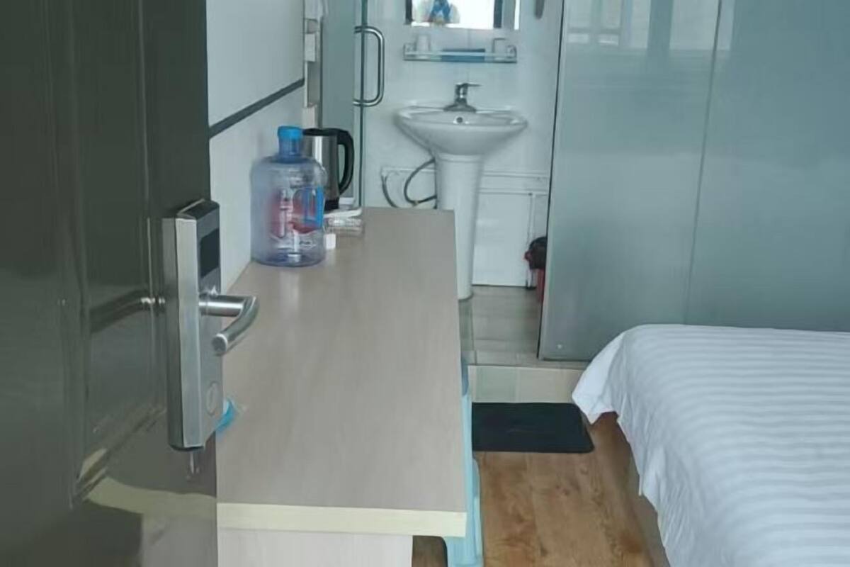 Une chambre d’hôtel avec un lit, une table de chevet avec une bouteille d’eau, un lavabo et un miroir.