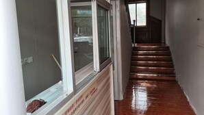 Een gang met een houten trap, een raam met uitzicht en een bord aan de muur.