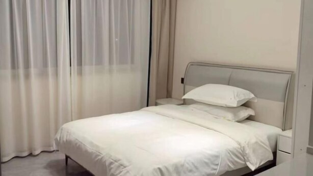 A bed with a headboard, a bedside table, and a curtain.