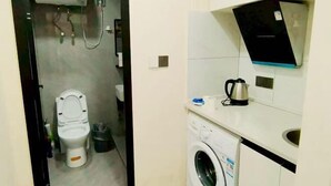 A compact bathroom with a toilet, washing machine, and a sink.