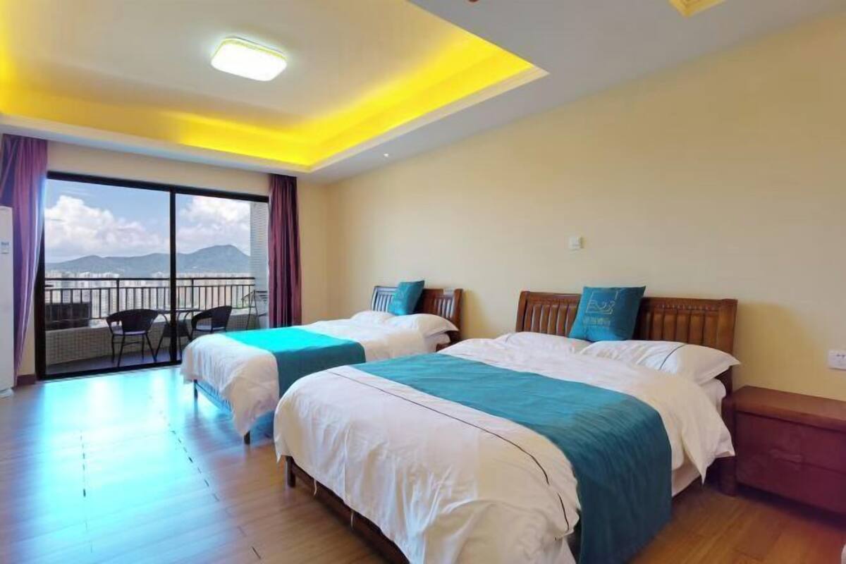 Een hotelkamer met twee bedden, een balkon met uitzicht en een plafondlamp.