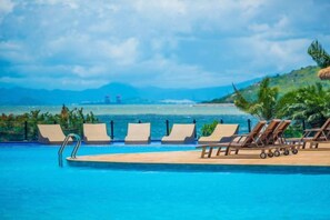Une piscine avec des chaises longues et vue sur la mer.