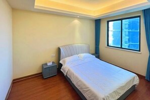 A bedroom with a bed, nightstand, and a window with curtains. - Linghai Seaview Apartment (Huizhou Huidong Shili Yintan Shop) (Huidong)