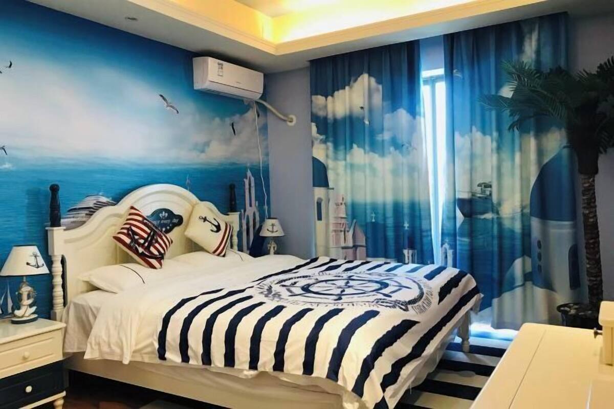 Een slaapkamer met een bed, nachtkastjes, een wandairconditioner en een raam met gordijnen.