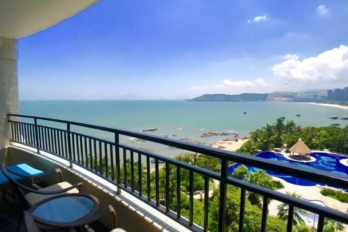 Een balkon met uitzicht op een strand, zwembad en resort.