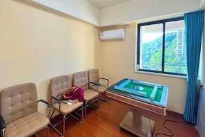 Ein Zimmer mit Billardtisch, vier Stühlen, einem Fenster mit Blick auf Grünflächen und einer Klimaanlage.
