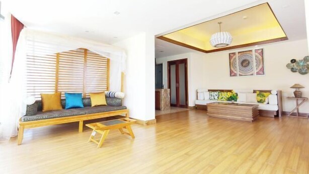 A spacious living room with a wooden floor, a sofa with cushions, a coffee table, and a ceiling light fixture. - Linghai Seaview Apartment (Huizhou Huidong Shili Yintan Shop) (Huidong)