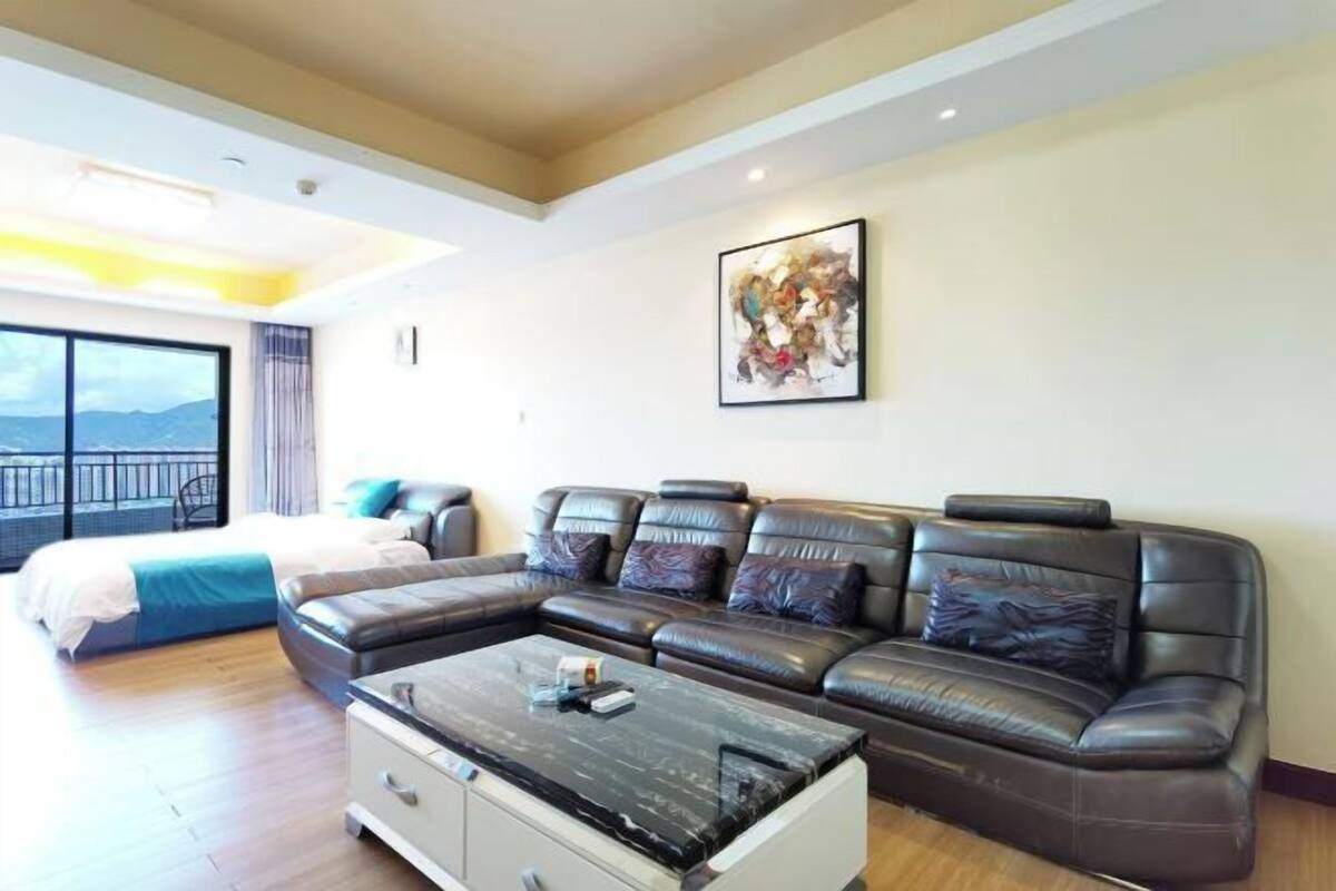 Een moderne woonkamer met een hoekbank, een salontafel en een bed met uitzicht.