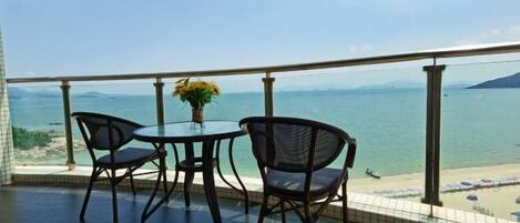 A balcony with a table and chairs overlooking a beach.