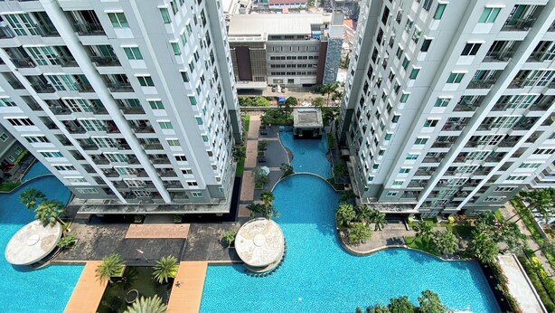 A high-rise building with a swimming pool and surrounding greenery. - Spacious and Nice 2BR Apartment (Executive City Home unit) at Thamrin Residence (Jakarta)