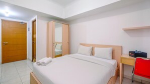 A hotel room with a bed, a desk, a chair, and a wardrobe.
