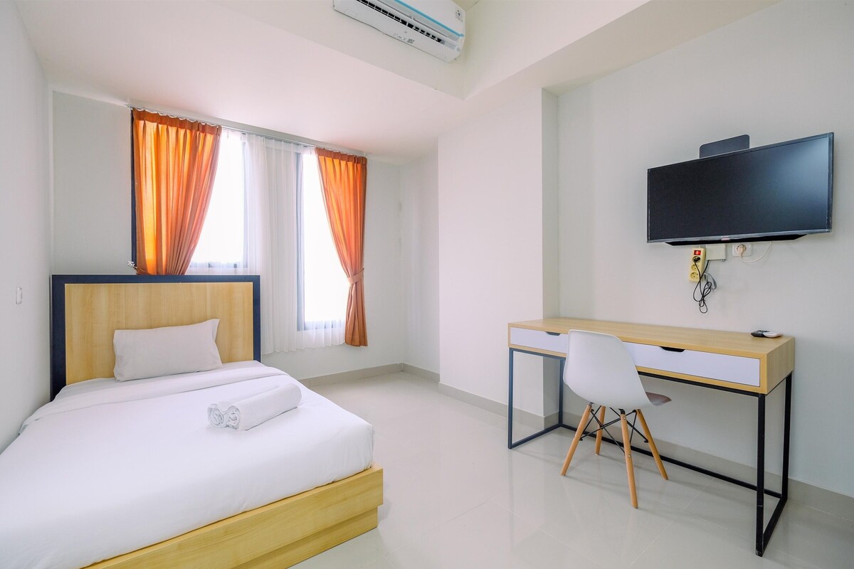 Una habitación de hotel con cama, escritorio, silla, televisor y aire acondicionado.