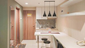 A compact kitchen with a central island, pendant lights, and a built-in stove. - Good and Homey Studio at Student Park Yogyakarta Apartment (Depok)