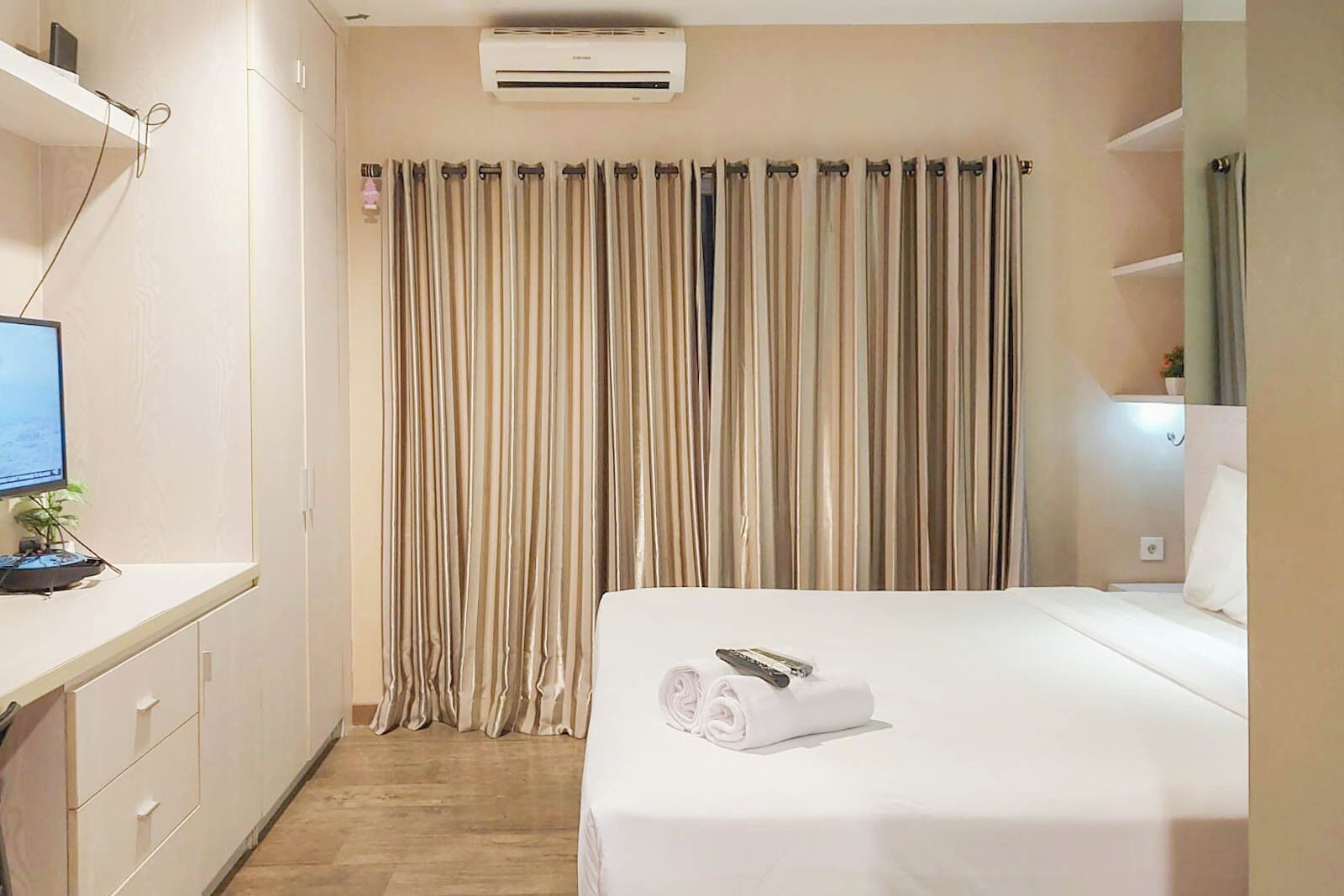 A hotel room with a bed, a desk with a computer, and a curtain.