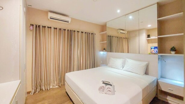 Ein Hotelzimmer mit einem großen Bett, einem Nachttisch, einem Spiegel und einem Fenster mit Vorhängen.