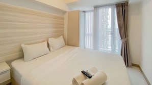 Habitación de hotel con una cama grande, una mesita de noche, una ventana con cortinas y vistas al exterior.