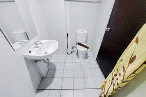 A small bathroom with a sink, toilet, and a mirror. - Cozy and Enjoy Living Studio Casa De Parco Apartment (Pagedangan)