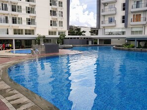 A modern residential building with a swimming pool. - Cozy and Enjoy Living Studio Casa De Parco Apartment (Pagedangan)