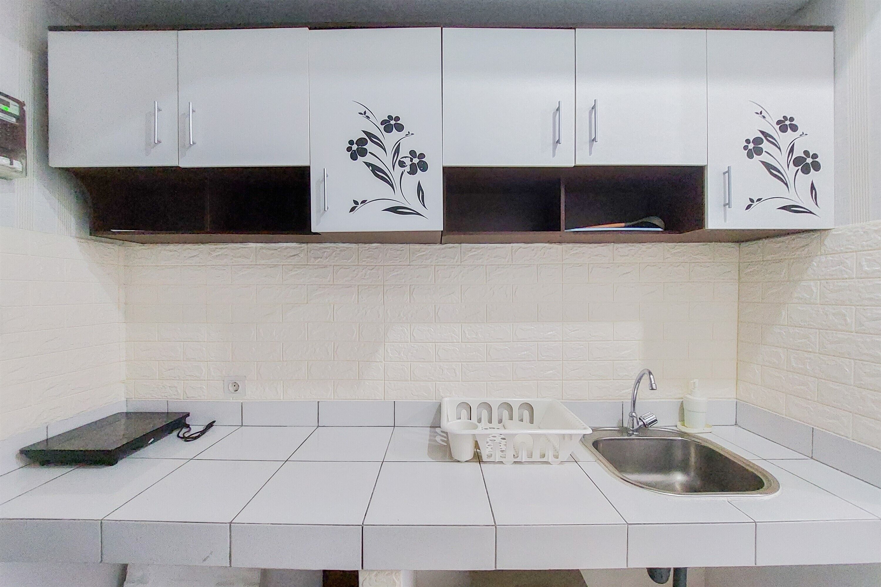 A kitchen with white cabinets, a stainless steel sink, and a white tiled backsplash.