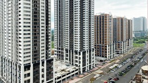 Un immeuble résidentiel de grande hauteur, composé de plusieurs étages, doté d’une cour intérieure et d’un espace de stationnement pour voitures.