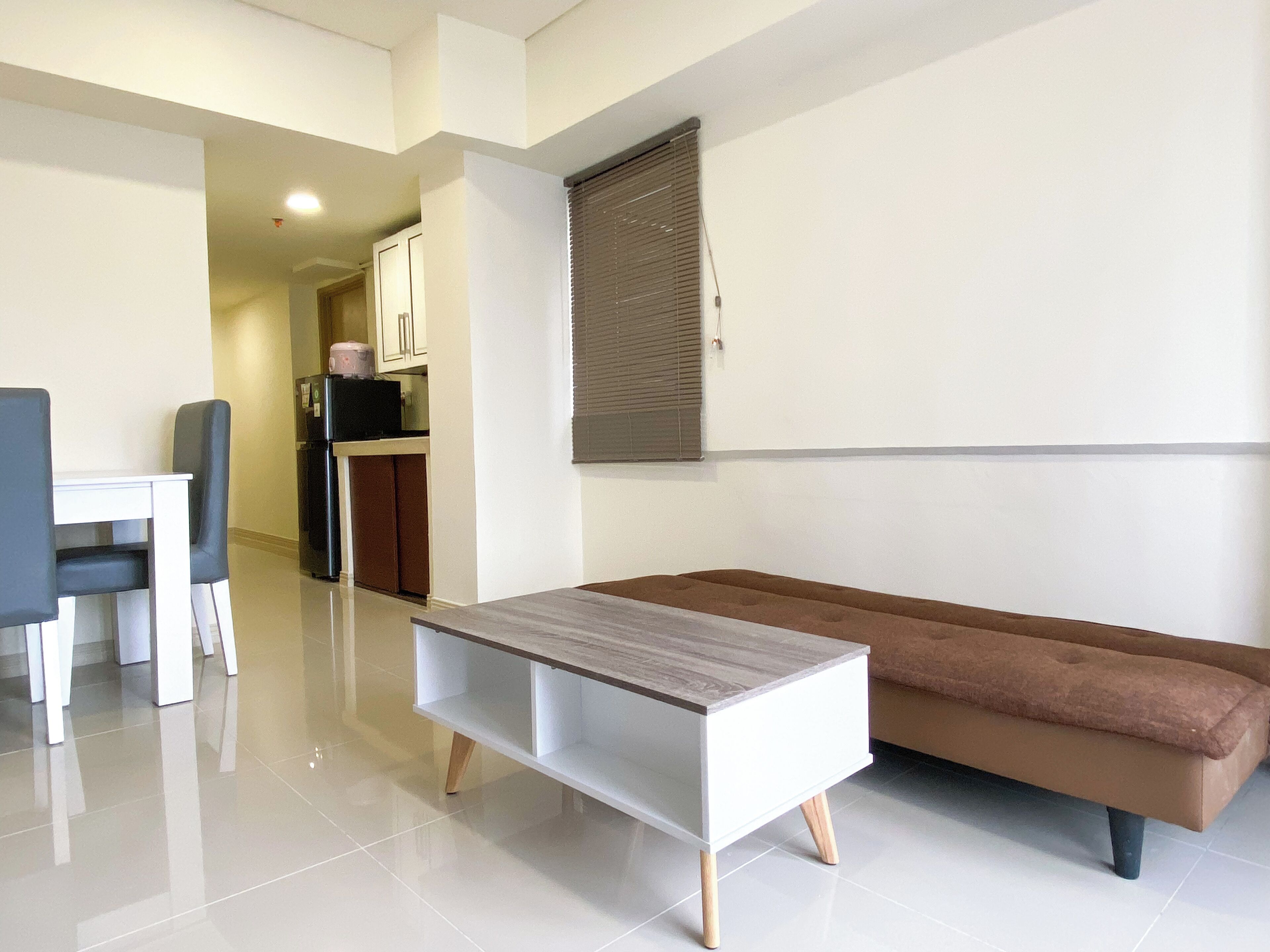 A modern living room with a sofa, a coffee table, and a dining area with chairs and a table.