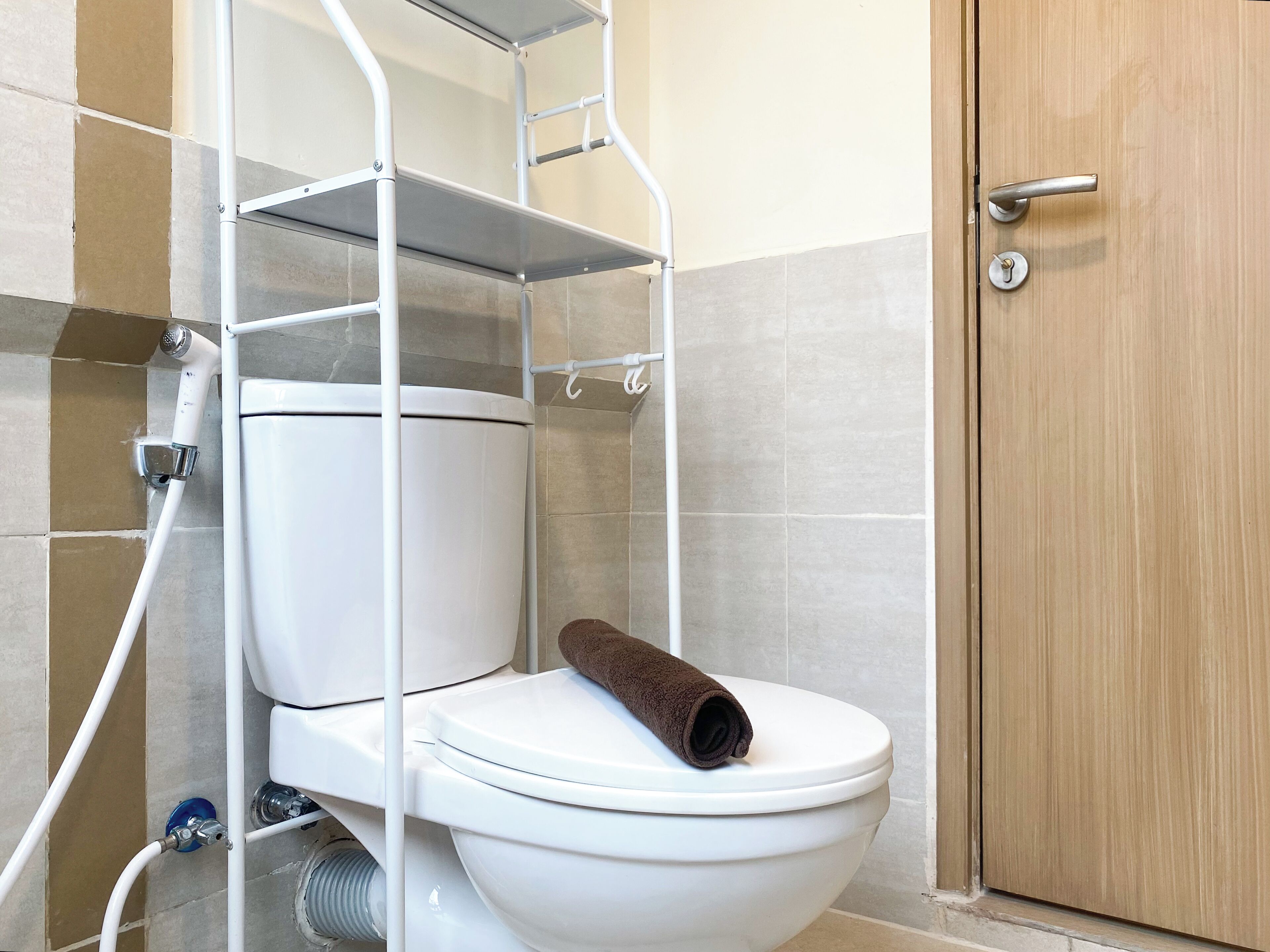 A bathroom with a white toilet, a towel on the seat, and a wooden door.