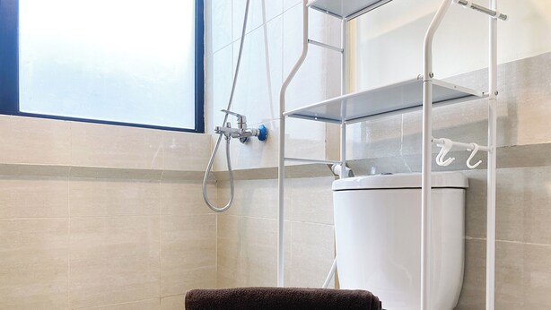 Een moderne badkamer met toilet, douchekop en raam.