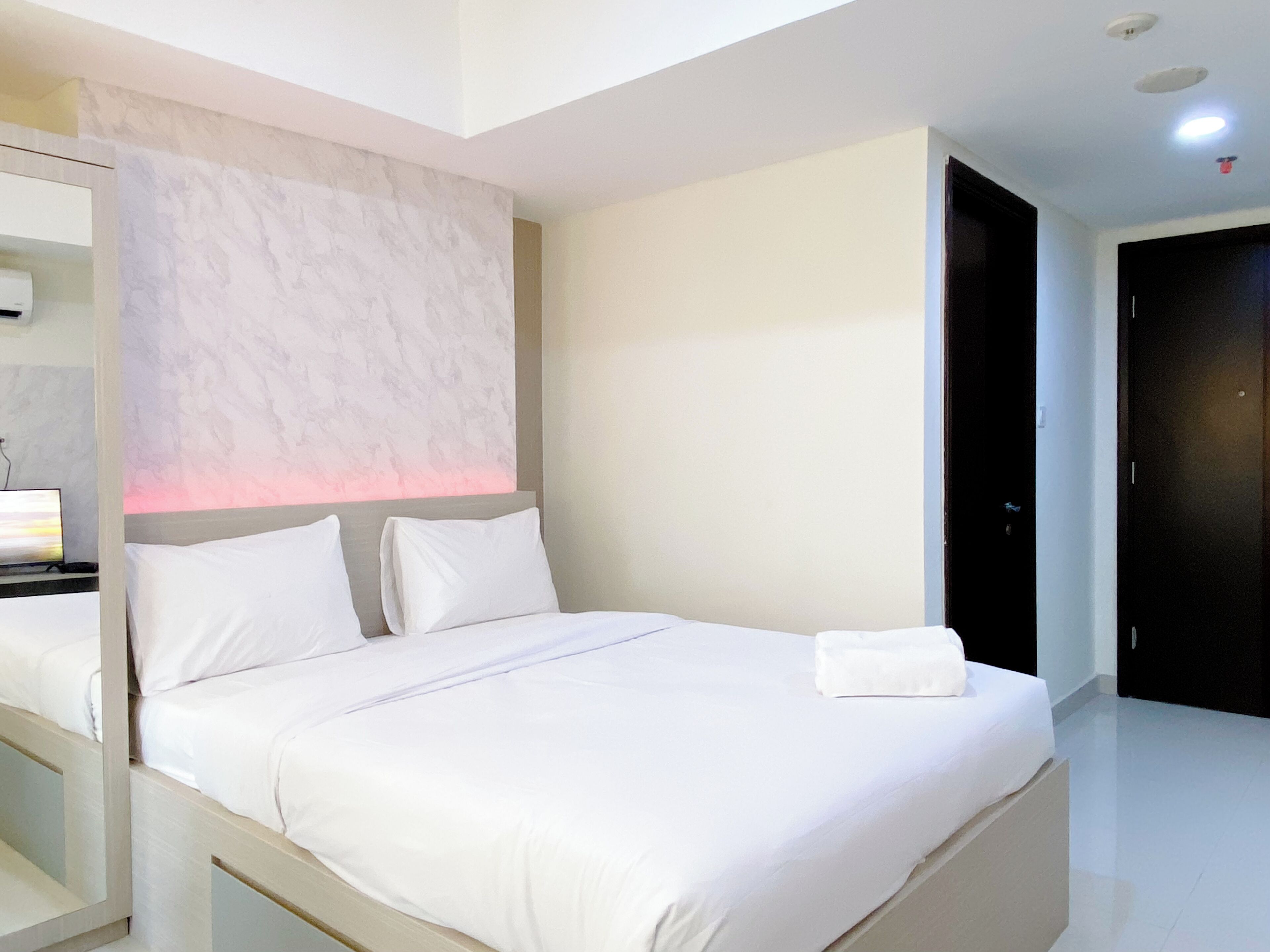Ein modernes Hotelzimmer mit einem großen Bett, einem Nachttisch und einem Spiegel.
