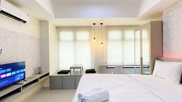 Quarto de hotel moderno com uma cama grande, uma escrivaninha e uma televisão.