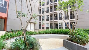 A courtyard with a circular garden, a modern building in the background, and a mix of greenery and architectural elements. - Enjoy and Cozy Living Studio Transpark Juanda Bekasi Timur Apartment (Bekasi)