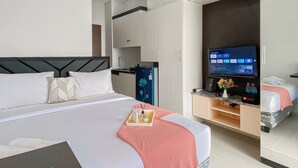 A hotel room with a bed, a TV, a desk, and a kitchenette. - Enjoy and Cozy Living Studio Transpark Juanda Bekasi Timur Apartment (Bekasi)