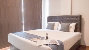 A neatly made bed with a grey headboard, white bedding, and a few pillows.