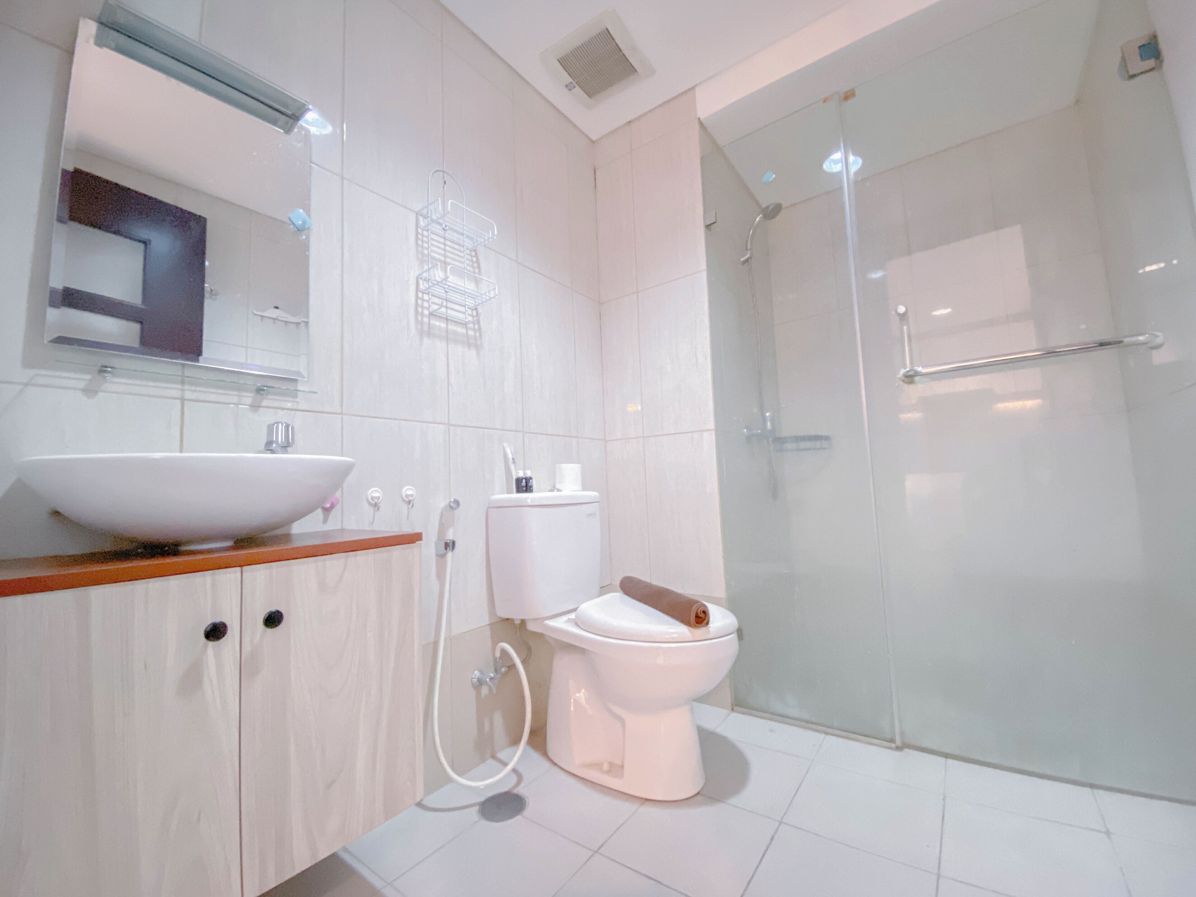 Un baño moderno con un lavamanos blanco grande, un inodoro y una cabina de ducha de vidrio.