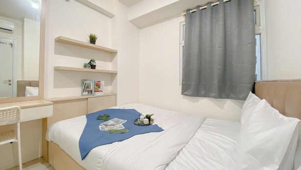 A bedroom with a bed, a desk, and shelves with plants. - Good Deal and Comfy 2BR Apartment Green Pramuka City (Jakarta)