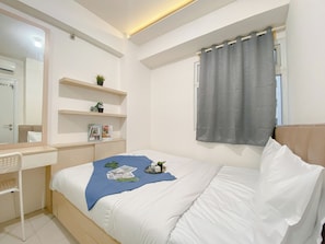 A bedroom with a bed, a desk, and shelves with plants. - Good Deal and Comfy 2BR Apartment Green Pramuka City (Jakarta)
