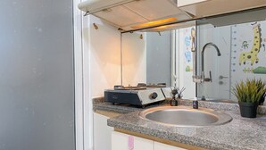 A kitchen with a granite countertop, stainless steel sink, and a stove. - Good Deal and Comfy 2BR Apartment Green Pramuka City (Jakarta)