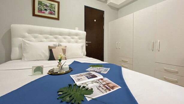 A hotel room with a large bed, a wardrobe, and a door. - Minimalist And Cozy 1BR at Royal Heights Apartment (Bogor)