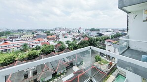 Un immeuble de grande hauteur doté de nombreux balcons, offrant une vue sur le paysage urbain et comprenant un mélange de logements et de commerces.