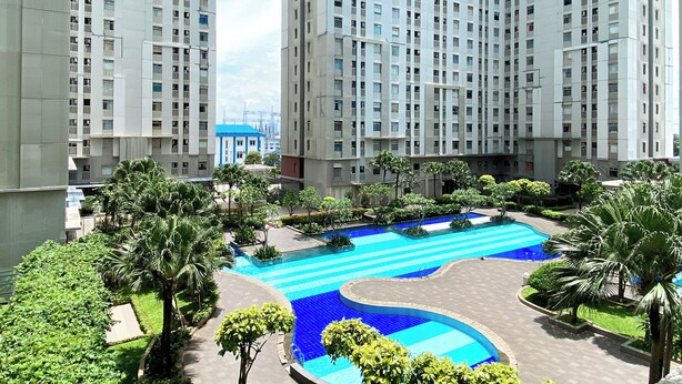A residential complex with high-rise buildings, a swimming pool, and landscaped areas.
