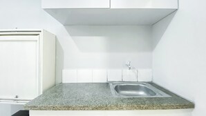 A kitchen with a granite countertop, a stainless steel sink, and white cabinets.