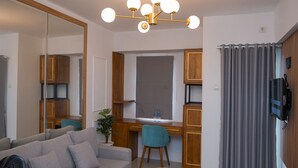 A modern living room with a sofa, a dining area with a table and chairs, a large mirror, and a ceiling light fixture. - Luxurious 2BR at Urbantown Serpong Apartment (South Tangerang)