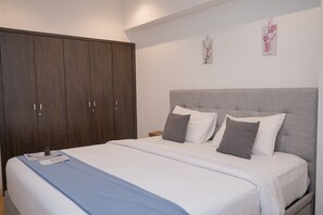 Quarto com uma cama grande, um guarda-roupa e duas obras de arte penduradas na parede.