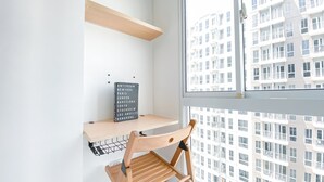 A small workspace with a wooden chair, a blackboard with city names, and a window overlooking a building. - Nice Room Studio Apartment at Tokyo Riverside PIK 2 (Teluknaga)