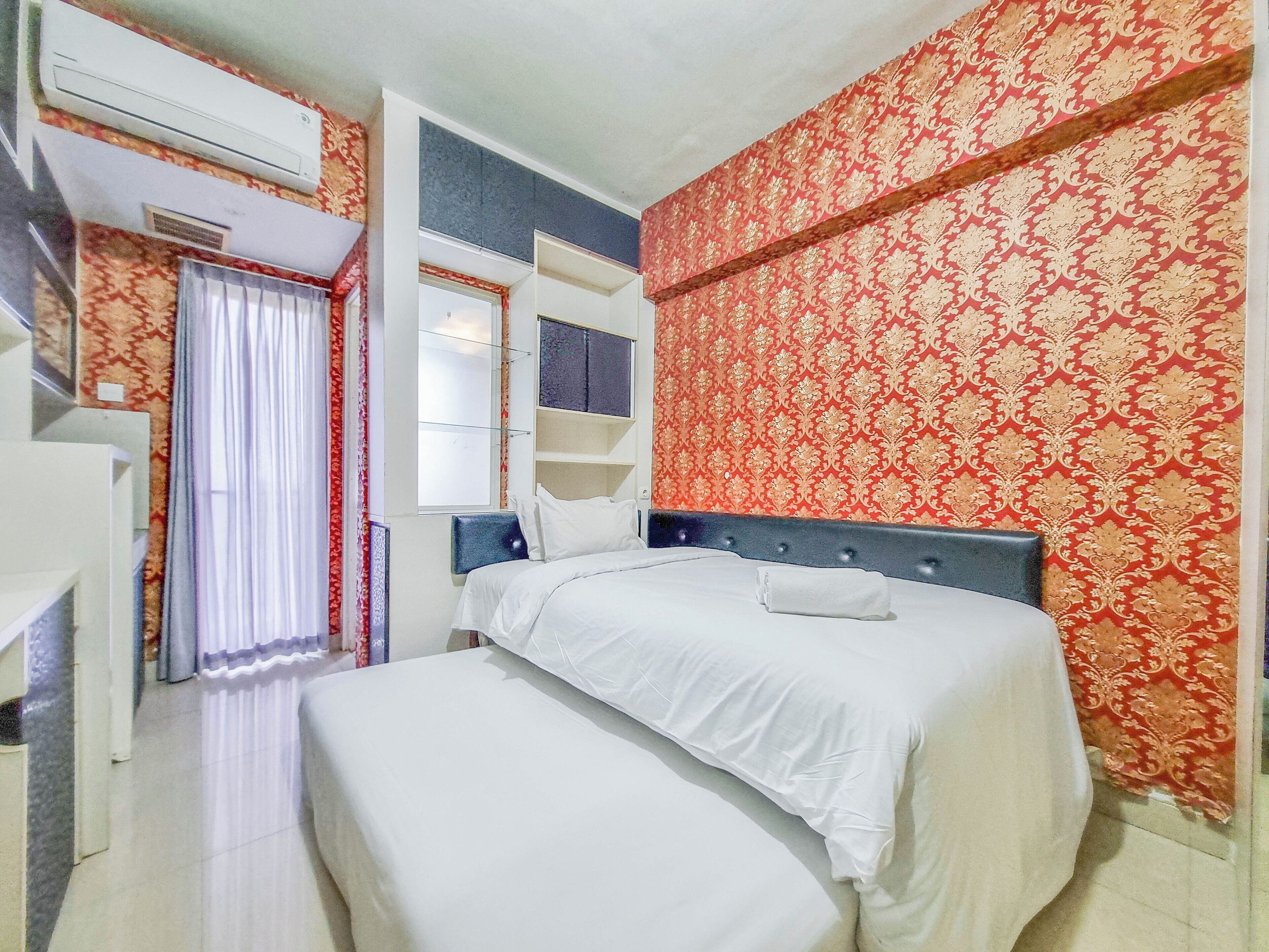 Habitació d'hotel amb llit, armari, mirall i finestra amb cortines.